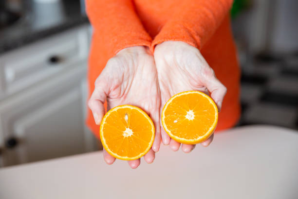 istock Two sliced orange pieces in hands 1223156842