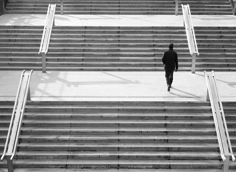 Man walking up a modern staircase in a city - monochrome picture
