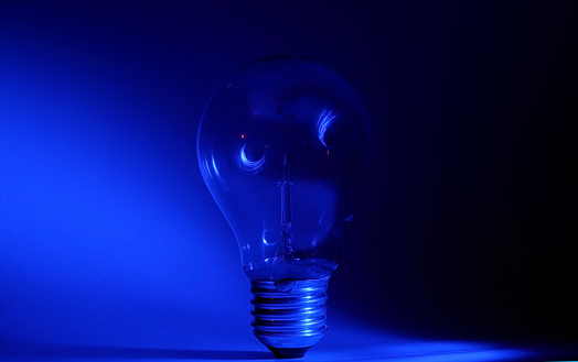 the light bulb without electricity that gives light in the bluish shade. blue background.