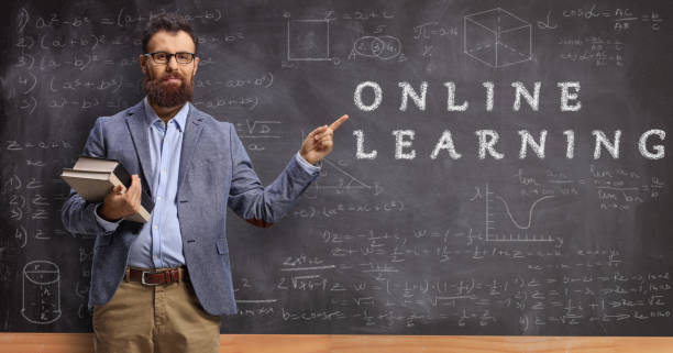 istock Male teacher holding books and pointing at a blackboard with text online learning 1223163343