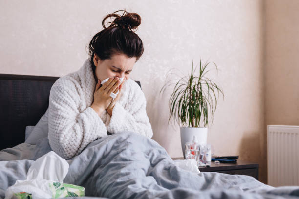 istock young sick woman in bed drinks pills 1223164034
