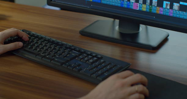 Close up of male video editor's hands as he works on an edit for a tight deadline and client in his home office. Close up of male video editor's hands as he works on an edit for a tight deadline and client in his home office adobe material stock pictures, royalty-free photos & images