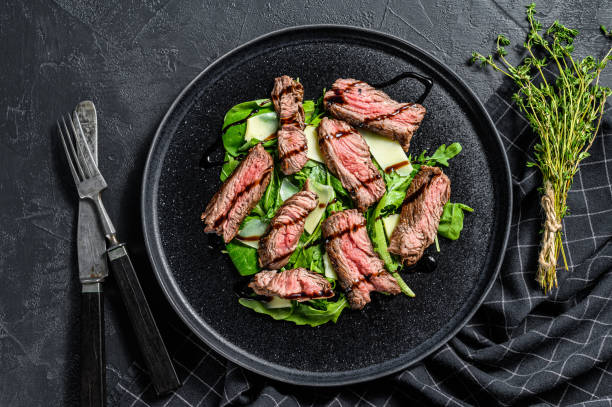 istock Steak salad with spinach, arugula and sliced beef Striploin steak. Black background. Top view 1223172216