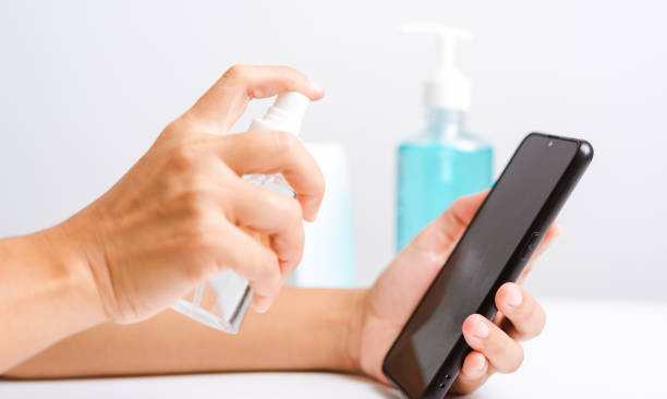 Asian young woman applying press dispenser sanitizer alcohol spray squirt to smart mobile phone wash cleaning, hygiene prevention COVID-19 or coronavirus protection concept, isolated white background mujer joven asiática que aplica dispensador de prensa dispensador de alcohol spray squirt a la limpieza de lavado de teléfono móvil inteligente, prevención de la higiene covid-19 o concepto de protección del coronavirus, fondo blanco aislado