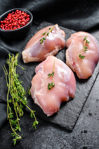 istock Raw boneless chicken thighs fillet. Black background. Top view 1223174140