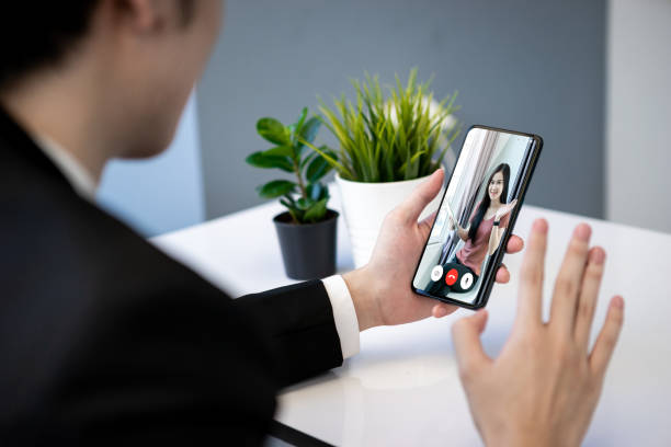 istock Asian business man dringking coffee wearing suit, enjoying watching educational webinar on laptop or laptop and smartphone. Smiling with chat and holding video call with clients partners. 1223174747