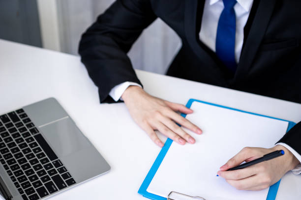 istock Asian business man dringking coffee wearing suit, enjoying watching educational webinar on laptop or laptop and smartphone. Smiling with chat and holding video call with clients partners. 1223174790