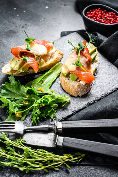 istock Toasts with avocado and smoked salmon.  Black background. Top view 1223175897