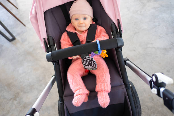 Top view of happy baby girl wearing pink Top view of happy baby girl wearing pink bodysuit and hat, sitting in pram and looking at camera. Infant child in stroller. Childhood or baby care concept buggy eyes stock pictures, royalty-free photos & images