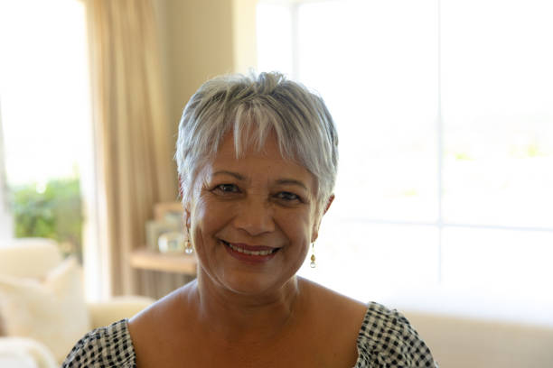 Self isolation in quarantine lock down. self isolation in quarantine lock down. portrait close up of a senior mixed race woman with short grey hair at home in front of a window and smiling to camera