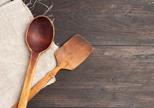 empty wooden spoon and spatula on a brown wooden background from boards, top view, copy space