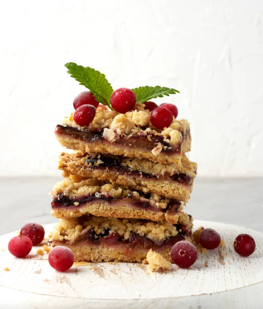 stack of square slices of baked crumble pie with blue plum on a white wooden board