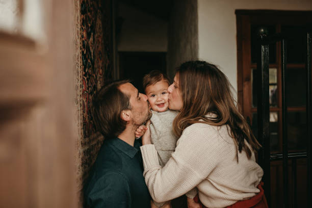 casal adorável beijando seu filho bebê em casa. - kissing child family isolated - fotografias e filmes do acervo