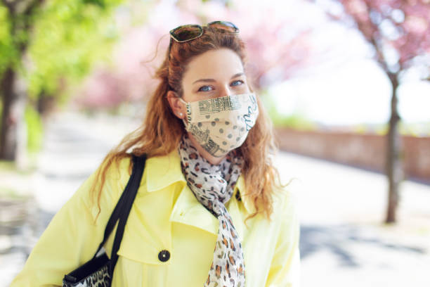 istock Young positive woman smiling under mask during springtime walk in park 1223191867