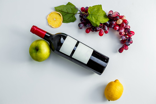 bottle of wine on a white background with grapes