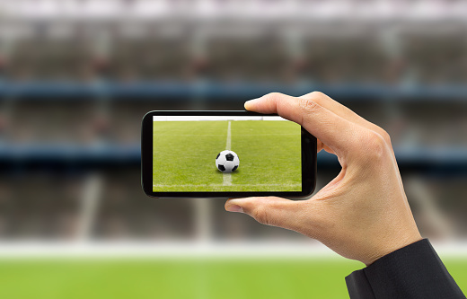 businessman photographing a soccer ball with the phone in a stadium