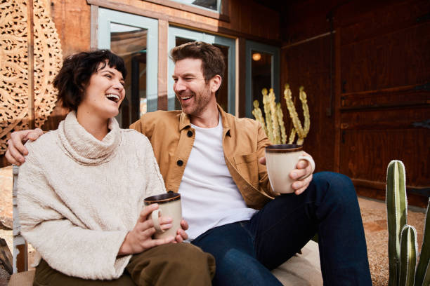istock Laughing young couple sitting outside their home talking over coffee 1223193586
