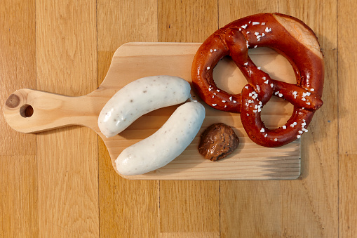 a pair of white sausages Bavarian style and brezn on a cutting board