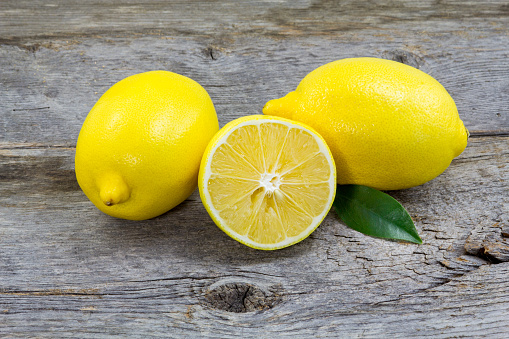 Lemons on a barn wood background. 2 full and a half one.