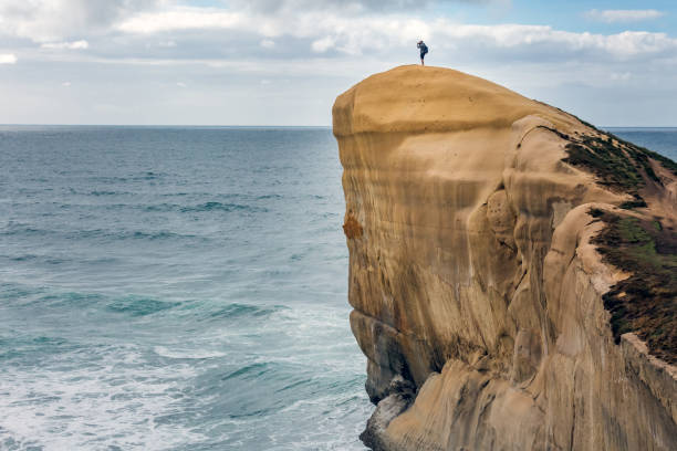 Man climbing on limestone near Tunnel beach at Dunedin, South island of New Zealand.
