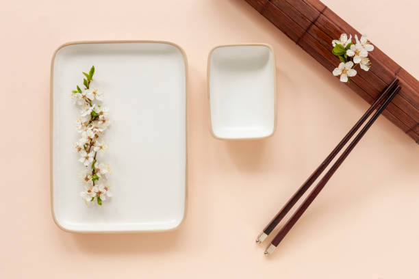istock Spring floral Japanese food concept with blooming cherry tree branches and serving with  chopsticks on coral color pastel paper background 1223205815