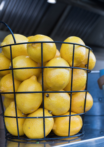 Yellow lemons in a metal basket during street food festival. Lemonade bar or terrace counter top table. Fruits rich in vitamin C good for juicing