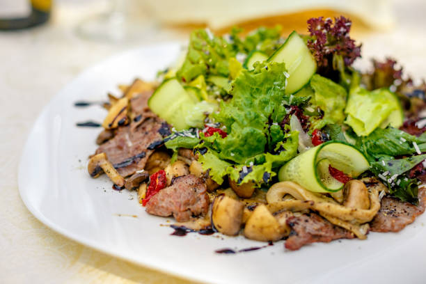 istock warm salad with meat, cucumber and vegetables on a white plate on the table 1223207391