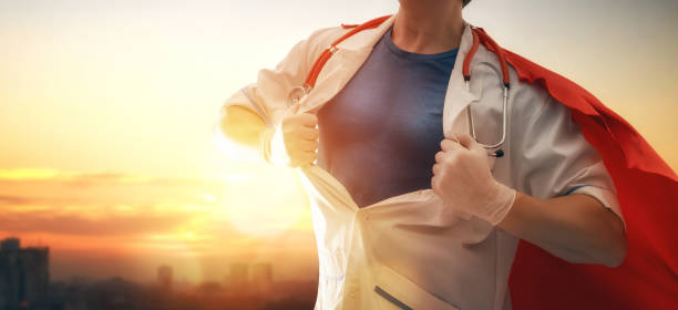 Doctor wearing facemask and superhero cape during coronavirus outbreak. Virus and illness protection, quarantine. COVID-2019. Super hero power for  medicine. Person on sunset cityscape background.