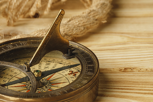 Ship rope and compass on wooden background, close up