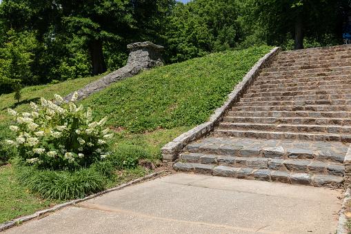 Rough granite block stairs and retaining wall on a hillside, urban park landscape, horizontal aspect