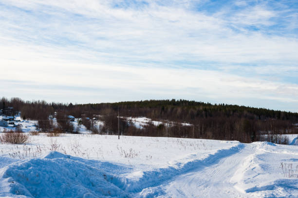 istock A view of the dirt road with a tractor tracks through the snow-covered fields. Dramatic blue sky. Forest in the background. Kuito lake, Karelia north, Lapland 1223219353