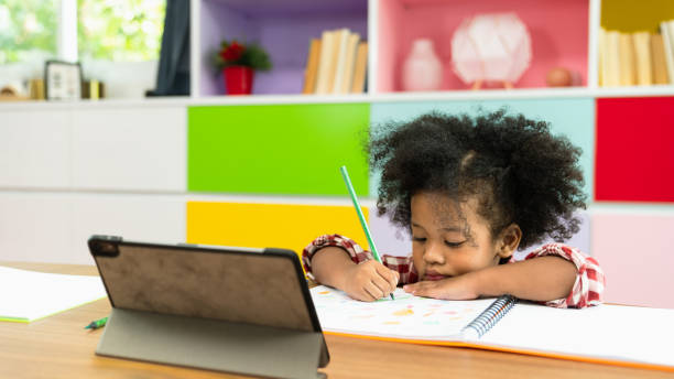 young african american kid girl studying using digital tablet, preschool child study at home school. children education, self isolation, coronavirus outbreak social distancing or homeschooling concept - homework pencil people indoors imagens e fotografias de stock