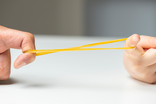 Father and her daughter are pulling rubber band. Close-up.