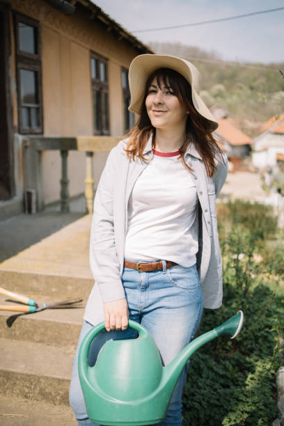 istock Smiling woman with hat holding watering can 1223225375