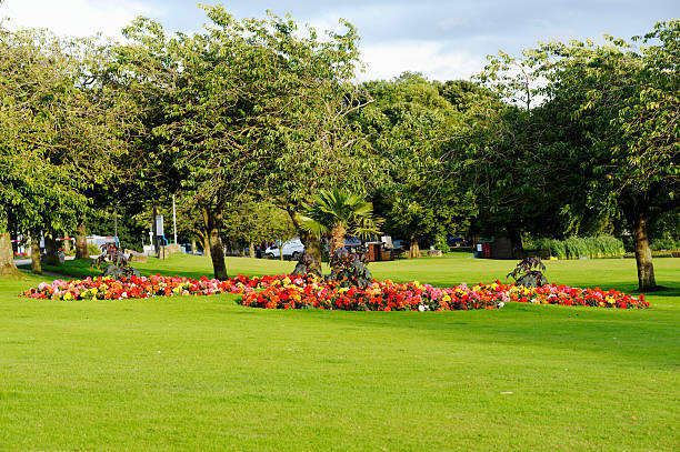 A public park in Scotland on a summer day with a colourful flower bed set in an area of grass
