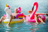 Elderly couple having fun on inflatable flamingo and unicorn
