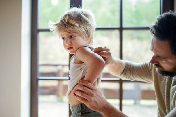 père avec le petit fils malheureux malade à l’intérieur à la maison, vérifiant son dos. - eczema photos et images de collection