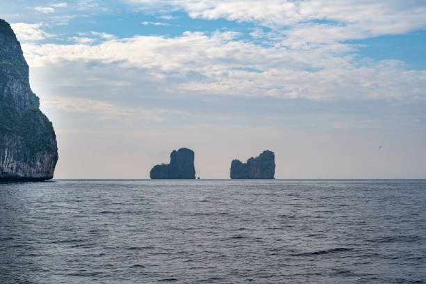 Limestone mountains in the Andaman Sea near the Krabi and Phuket provinces of Thailand, seen a summer day with some clouds in the sky.