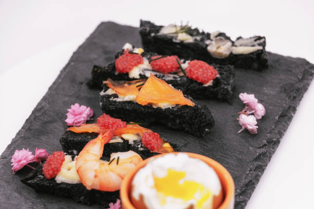 炭の黒パン粉とサーモンの塊の卵とバターとディルとスレートの盛り合わせにゆで卵のためのディル - フランスの美食 - prepared fish lumpfish caviar caviar smoked salmon ストックフォトと画像
