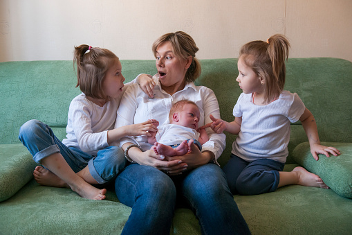 A mother with many children communicates with her three children sitting on the couch.