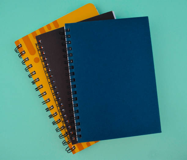 einige verschiedenfarbige papiertagebücher auf einem hellblauen isolierten papierhintergrund isoliert - spiral notebook stock-fotos und bilder