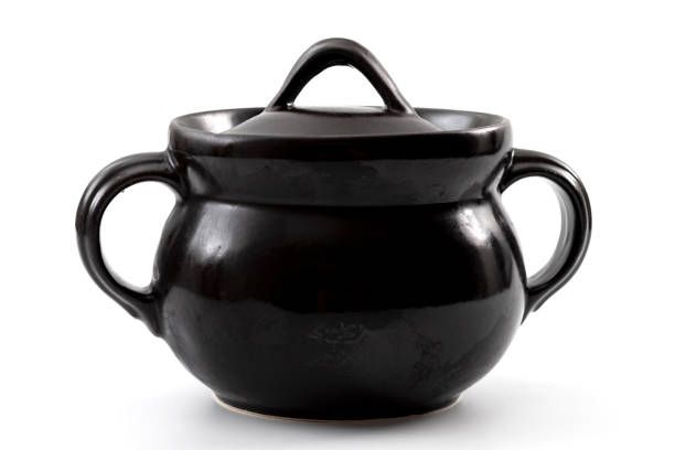 istock Pottery cookware and traditional rustic kitchenware concept with single black terracotta pot with handles and lid isolated on white background with clipping path cutout 1223237553