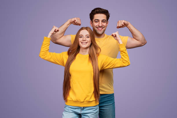 Cheerful young couple flexing muscles