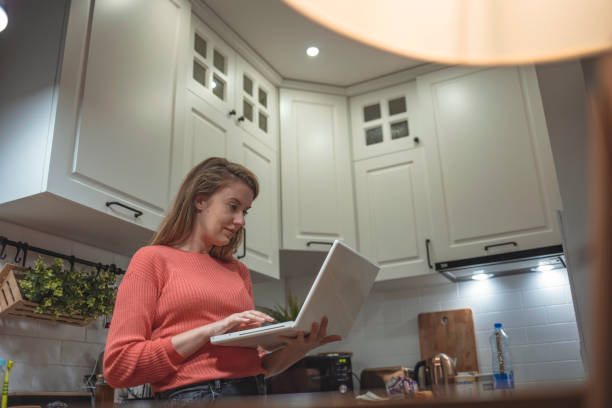 istock Young woman sitting in her kitchen working on a laptop. 1223240400