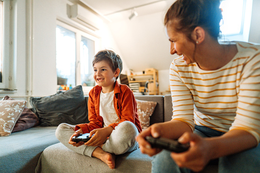 Photo of mother and son playing video games at home