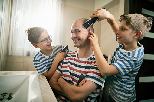 Father and son having fun together. Sons are cutting the father's hair. 
Nikon D850