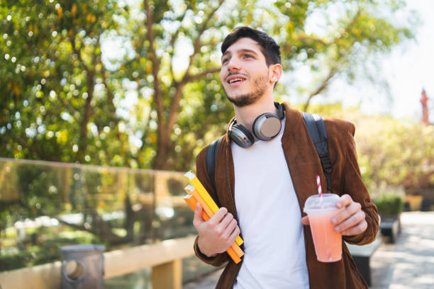 istock University student walking on the street while holding his books. 1223240961