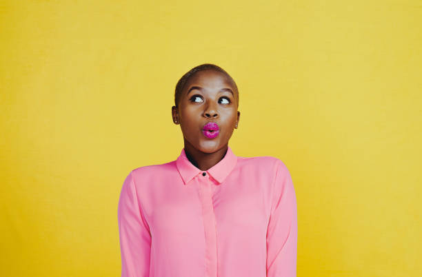 I'm just minding my own business Cropped shot of an attractive young woman whistling and feeling curious against a yellow background shaved black women stock pictures, royalty-free photos & images