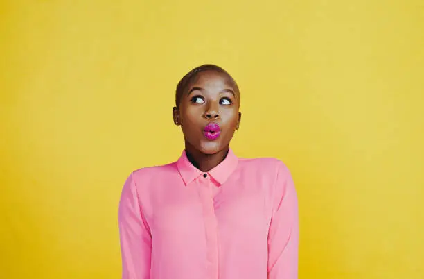 Cropped shot of an attractive young woman whistling and feeling curious against a yellow background