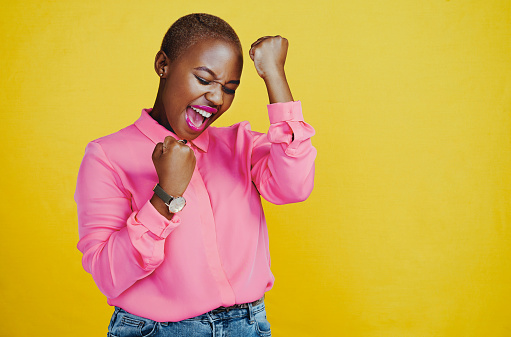 Cropped shot of an attractive young woman celebrating and feeling cheerful against a yellow background